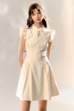 Woman in a cream dress with ruffle sleeves and embroidery in a studio