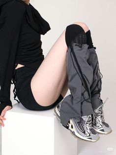 Person in a black hoodie and shorts with gray pants and sneakers