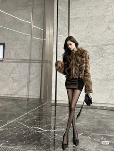 Woman in a fur coat and mini skirt standing indoors