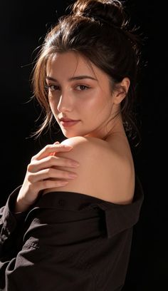 Woman with dark hair in a messy bun, wearing an off-shoulder shirt