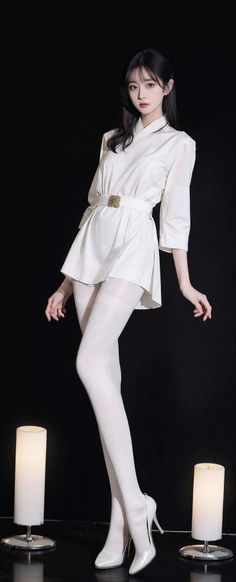 Woman in a white dress and stockings posing in a studio with soft lighting