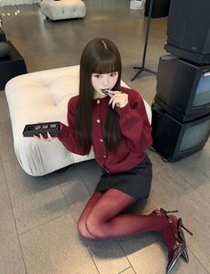 Woman in a red cardigan and black mini skirt with red tights and heels