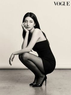 Woman in a black dress and heels squatting in a studio