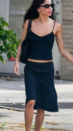 Woman in a black top and skirt walking outdoors