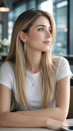 Woman with long blonde hair wearing a white t-shirt and silver jewelry indoors