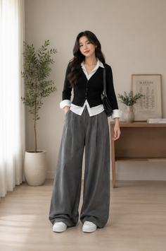Woman in a black cardigan and wide leg pants standing indoors
