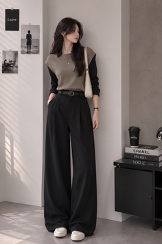Woman in a collared shirt and wide leg pants posing indoors