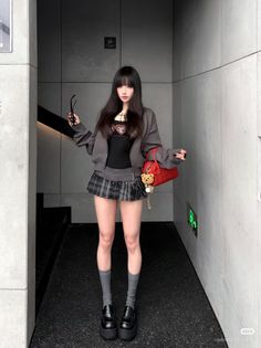 Woman with long black hair wearing a plaid skirt and cropped jacket indoors