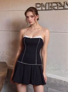 Woman in a black pinstripe dress with lace trim and spaghetti straps indoors