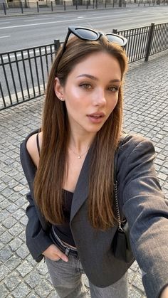 Woman with long hair and sunglasses on her head taking a selfie outdoors