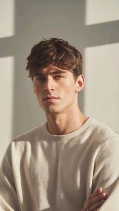 Man with brown hair wearing a light-colored crew neck sweater indoors