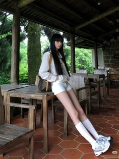 Woman with long black hair in white shorts and shirt at an outdoor cafe