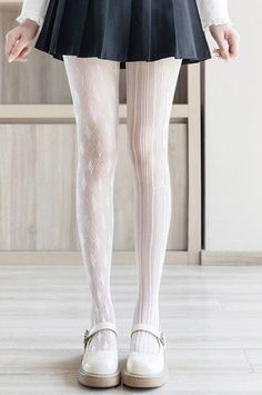 Person wearing white patterned tights, a black pleated skirt, and white mary jane shoes