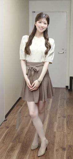 Woman with long brown hair wearing a blouse and mini skirt indoors