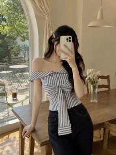 Woman in a striped off-shoulder top taking a selfie indoors