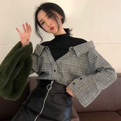 Woman in a plaid shirt and leather skirt with a green fur bag