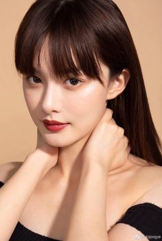 Woman with long hair and bangs wearing an off-shoulder top, hands around her neck