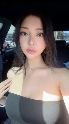 Woman in a tube top with long hair and hoop earrings in a car