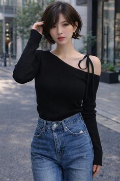 Woman with short hair wearing a black off-shoulder top and blue jeans outdoors