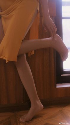 Person in a yellow dress with exposed leg and bare feet indoors