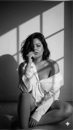 Woman in an unbuttoned white shirt with dramatic lighting in black and white