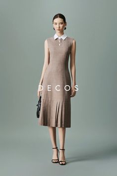 Woman in a sleeveless brown dress with a white collar and pleated skirt