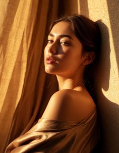 Woman with bare shoulders in golden hour light, leaning against a wall