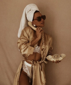 Woman in a satin robe and lace lingerie with a towel on her head and sunglasses