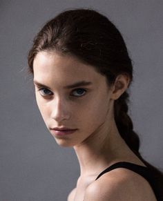 Young woman with dark braided hair and blue eyes in a black top