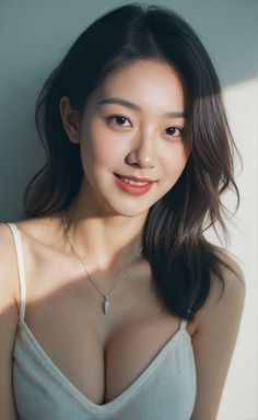 Woman with long dark hair wearing a white top and necklace, smiling at the camera