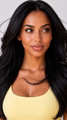 Woman with long black hair and freckles wearing a yellow top