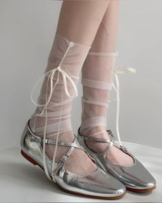 Legs wearing silver shoes and sheer socks with ribbon ties