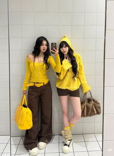 Two women in yellow tops and brown bottoms taking a mirror selfie