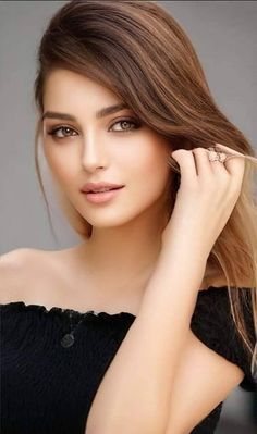 Woman with long brown hair wearing an off-shoulder top and a ring