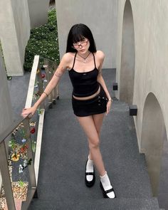 Woman in a black mini skirt and halter top posing on outdoor stairs