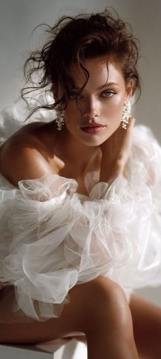 Woman in a white ruffled dress with sparkling earrings and soft lighting