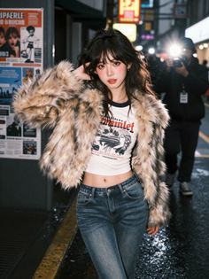 Woman in a faux fur coat and crop top on a street at night