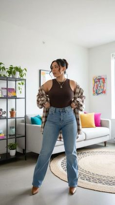 Woman in a plaid shirt and jeans posing in a modern apartment
