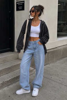 Woman in a crop top, baggy jeans, and hoodie on a street