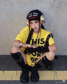Person with braided hair and headphones squatting on a street