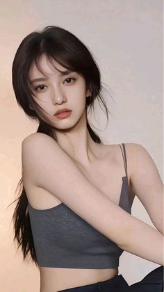Woman with long dark hair wearing a spaghetti strap top, looking at the camera