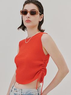 Woman in a red top and sunglasses with exposed midriff in a studio shot