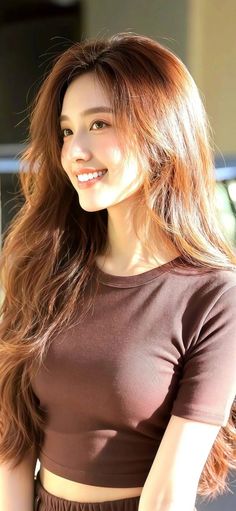 Woman with long brown hair wearing a brown cropped top in soft lighting