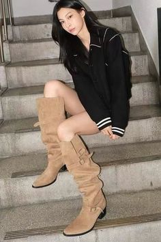Woman in a black shirt and tan boots sitting on concrete stairs