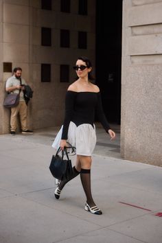 Woman in an off-shoulder top and black and white dress walking on a street