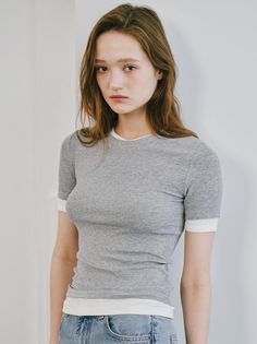 Woman with long hair wearing a grey t-shirt and jeans indoors