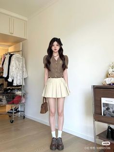 Woman in a brown top and pleated skirt standing indoors