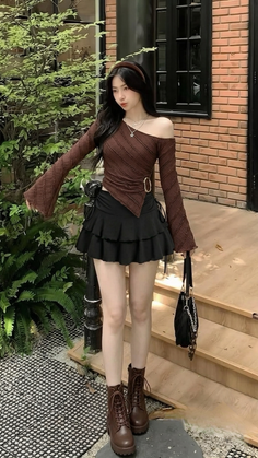 Woman in an off-shoulder top and mini skirt with brown boots and a handbag