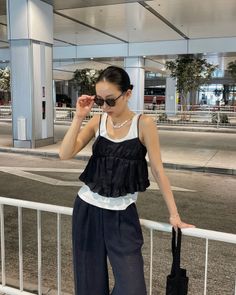 Woman in a black ruffled tank top and wide leg pants at night
