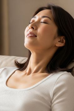 Woman with closed eyes and a relaxed expression in soft indoor lighting